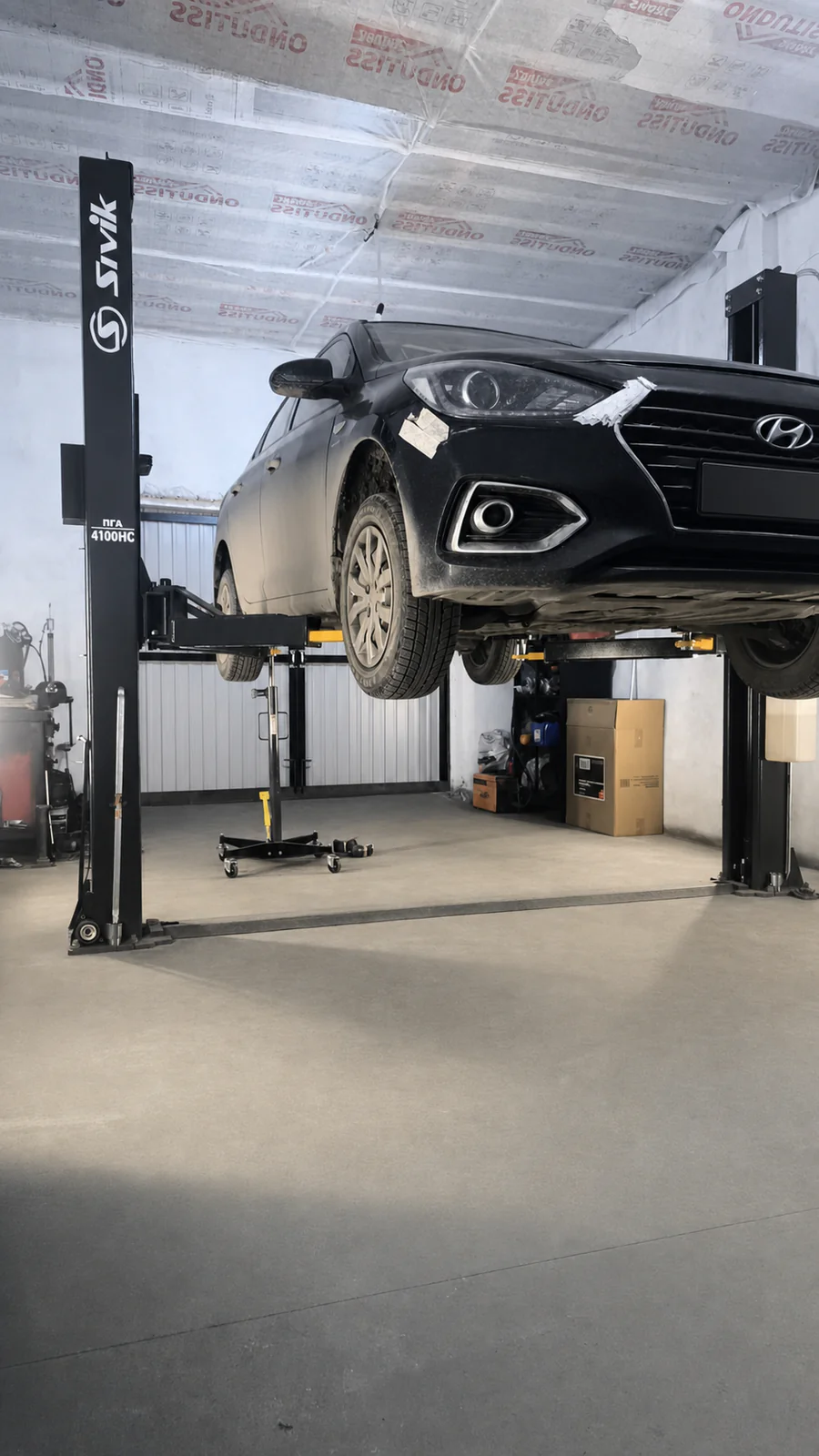 Чёрный автомобиль Hyundai на подъёмнике в мастерской